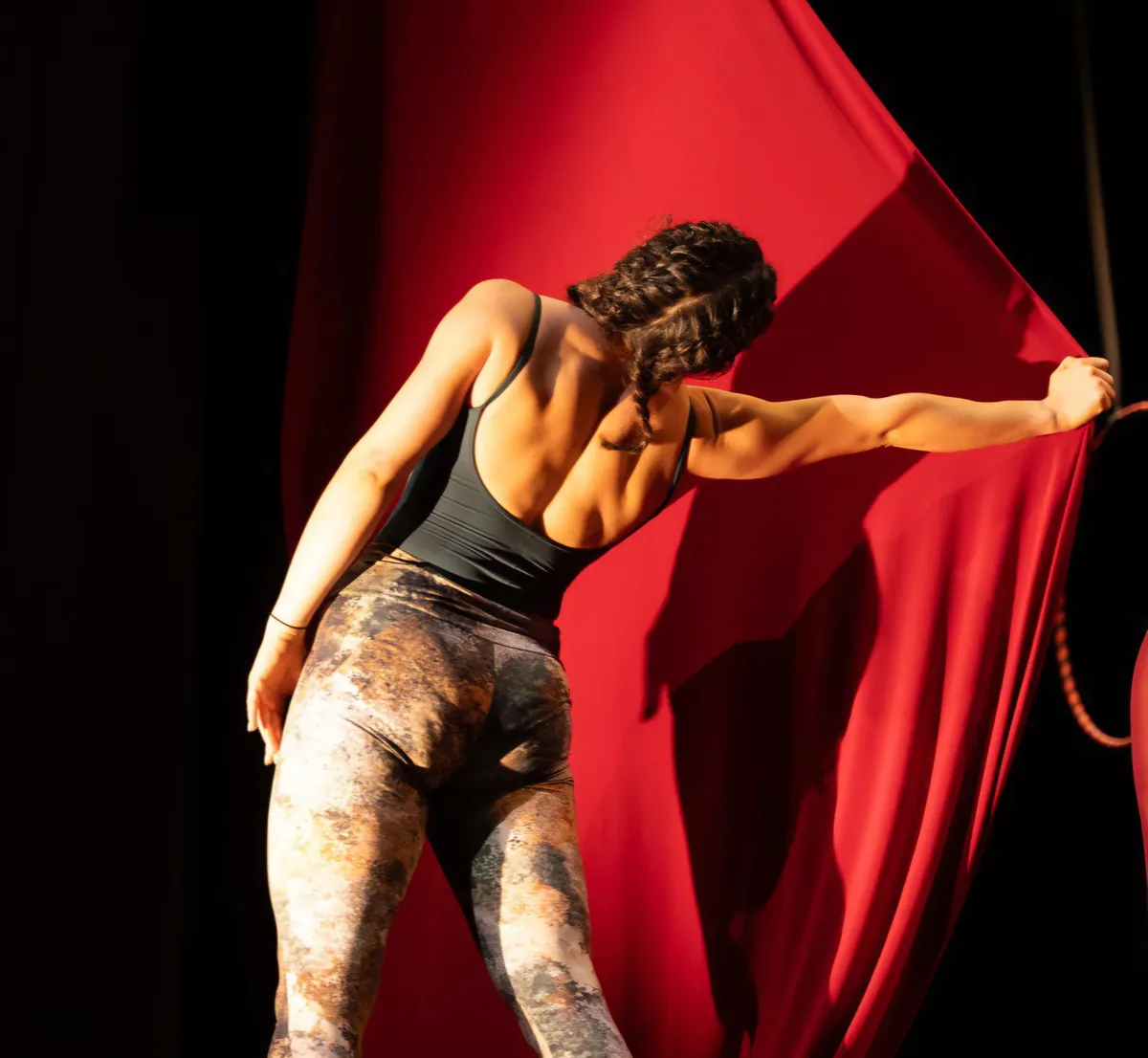 Istruttrice di spalle che si prepara a salire sul tessuto aereo rosso